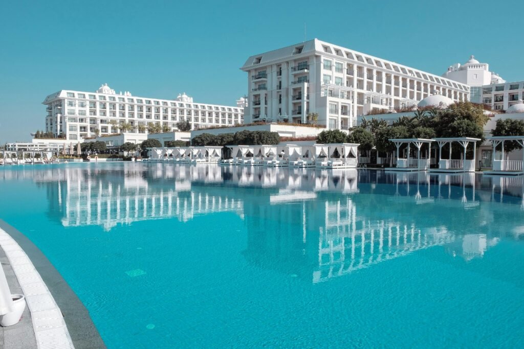 A breathtaking view of a luxurious hotel with a serene swimming pool reflecting the building and sky.
